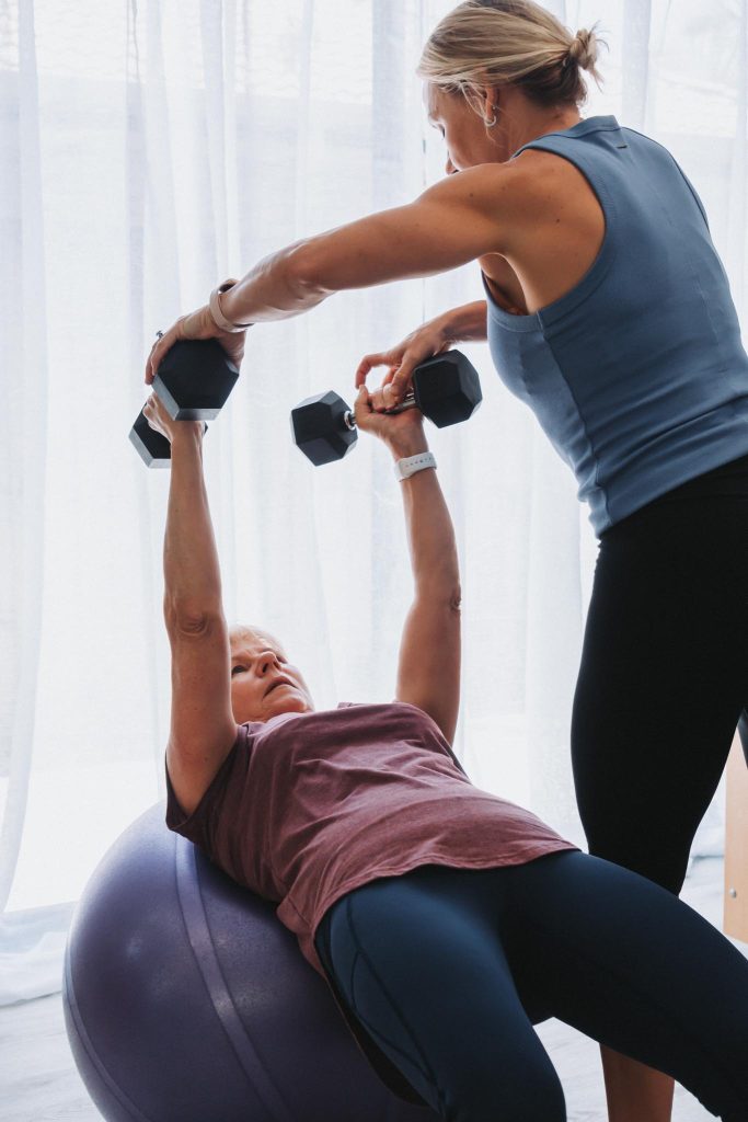 instructor helping a woman use weights for pilates class in Buderim